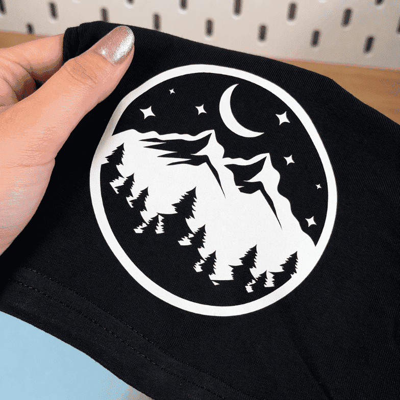 Motif montagne et lune en flex thermocollant phosphorescent blanc, de jour, sur un t-shirt noir