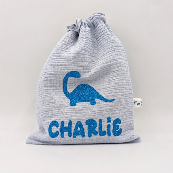 Pochon en gaze de coton gris avec dinosaure et prénom « Charlie » en flex pailleté bleu